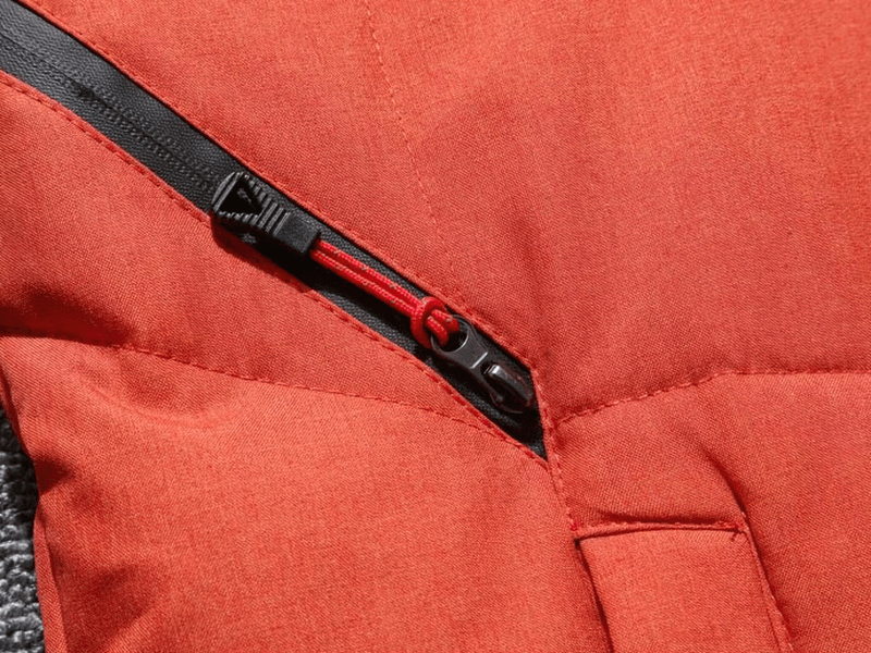 Close-up of orange waterproof ski suit with windproof zipper, perfect for winter sports